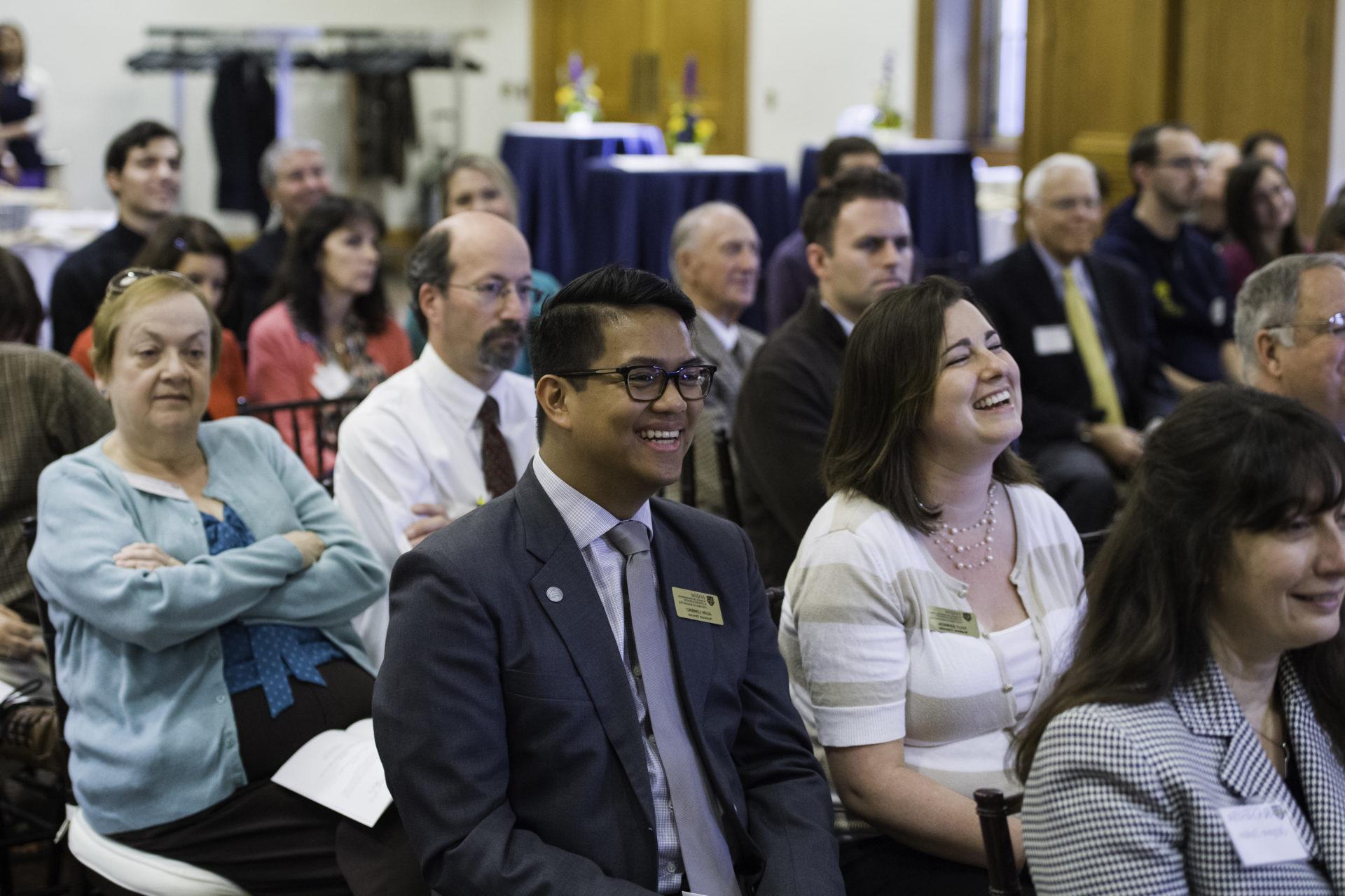 University faculty and staff laugh during a ceremony on the River Campus